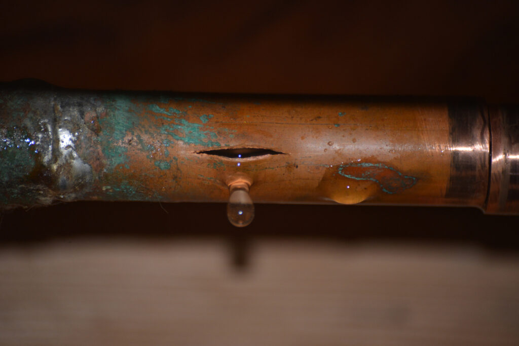 Copper pipe with a crack in it, leaking water.
