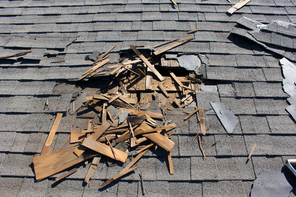 Roof with damaged shingles, exposing layer underneath.