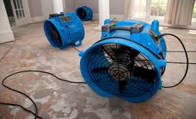 Large blue floor fans drying a wet carpet.