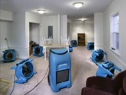 Large blue dehumidifiers in room for water damage restoration.