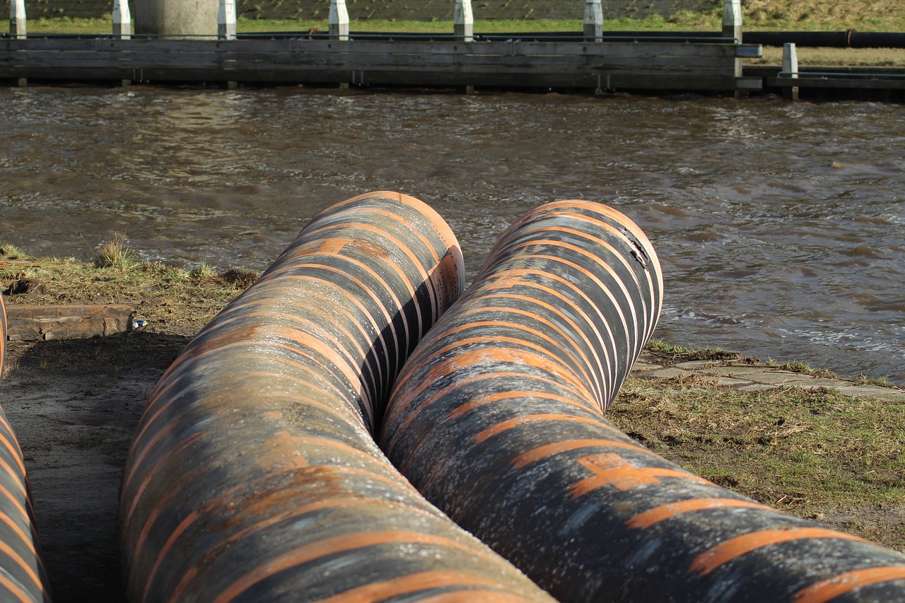 Two large sewage pipes ending at a body of water.