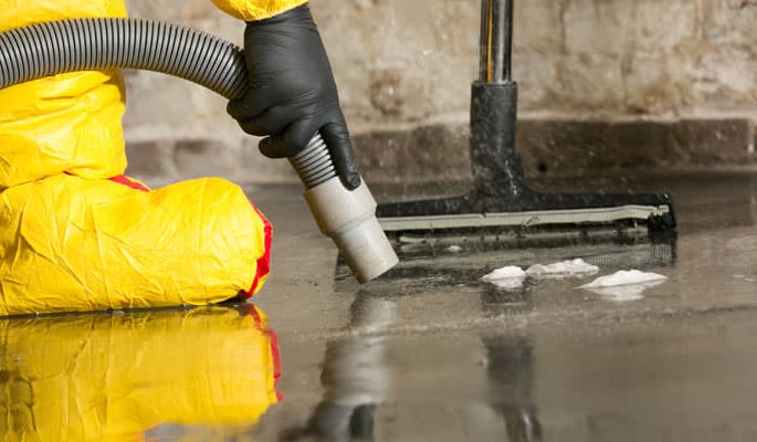 Technician's hand holding wet vac to the ground.