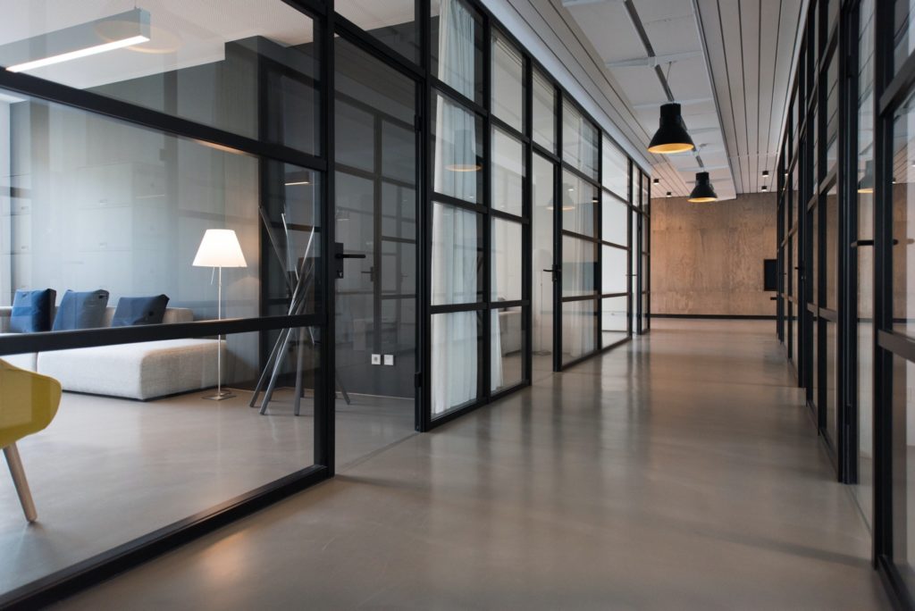 Interior of a commercial office building with glass walls and concrete floors.